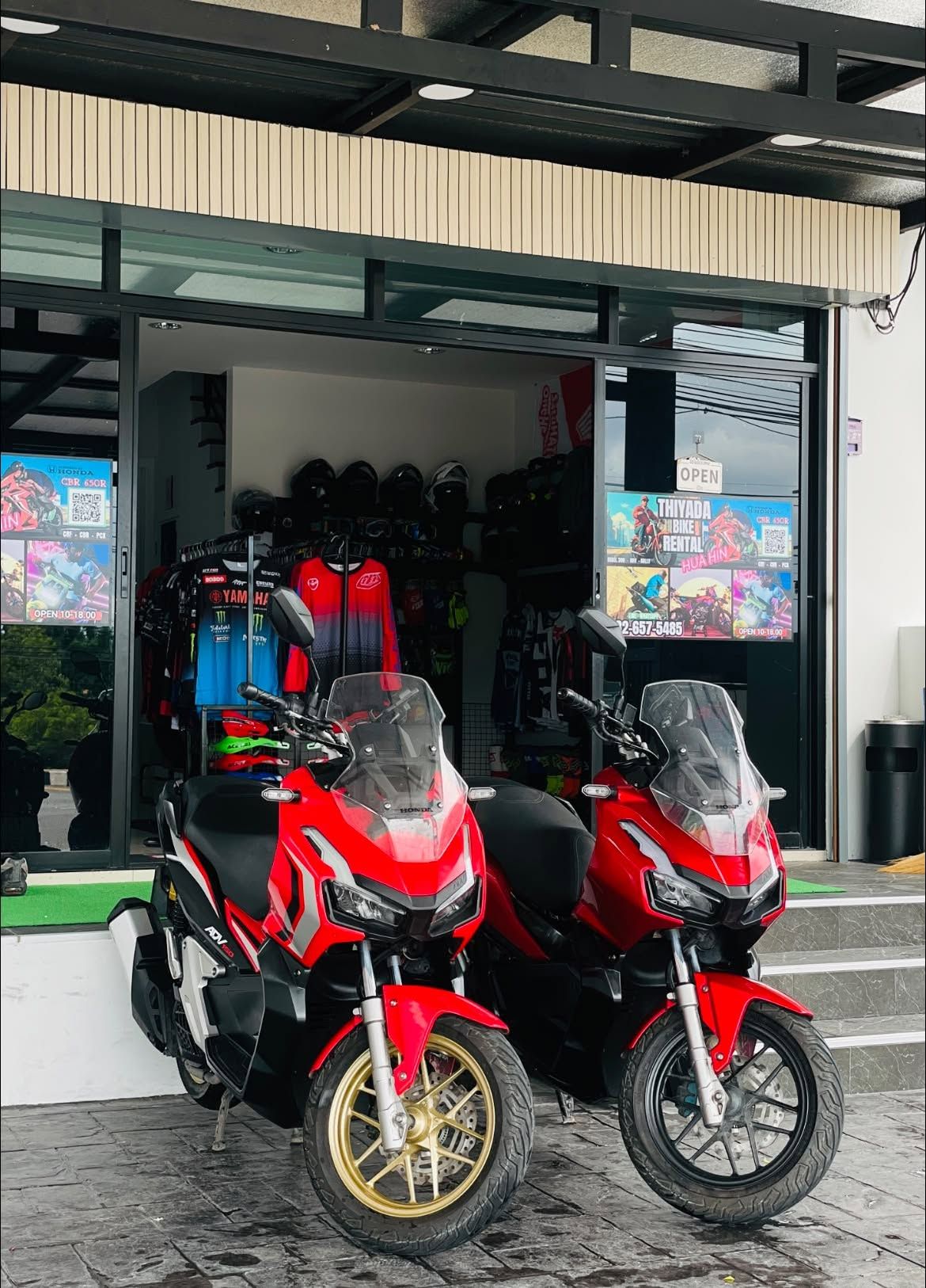 Two red Honda ADV160 adventure scooters outside the shop